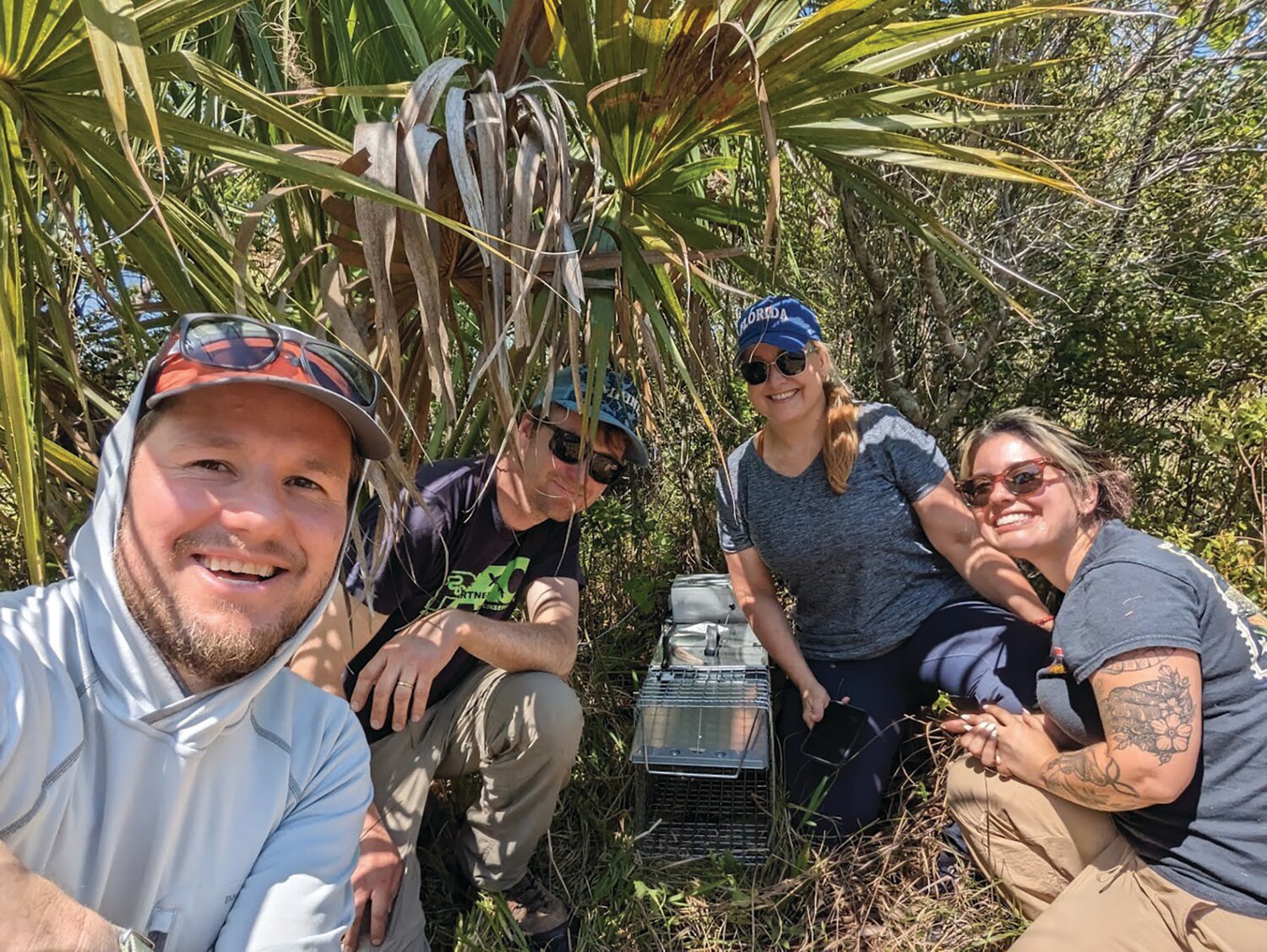Tegu team with designers: From left to right, Ben Stookey and Derek Yorks, developers of the AI smart traps, Melissa Miller, lead UF/IFAS researcher and Jenna Cole pause after field deployment of the first Ai smart trap for capture of invasive Argentine black and white tegus. [Photo courtesy UF/IFAS]